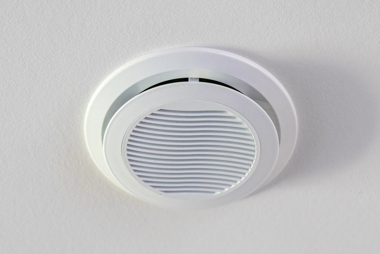 Schoon rond ventilatieventiel in een wit plafond