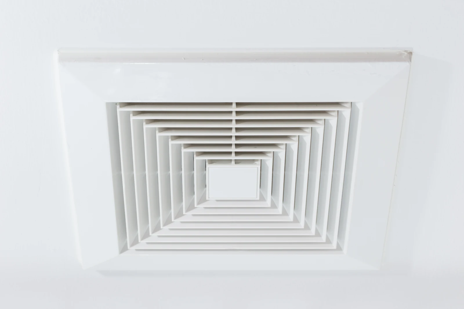 Schoon vierkant ventilatierooster in een wit plafond